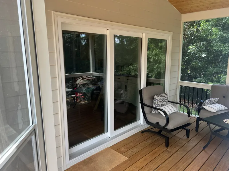 Inside a screened porch with sliding glass doors to the house, a tongue and groove ceiling and patio seating