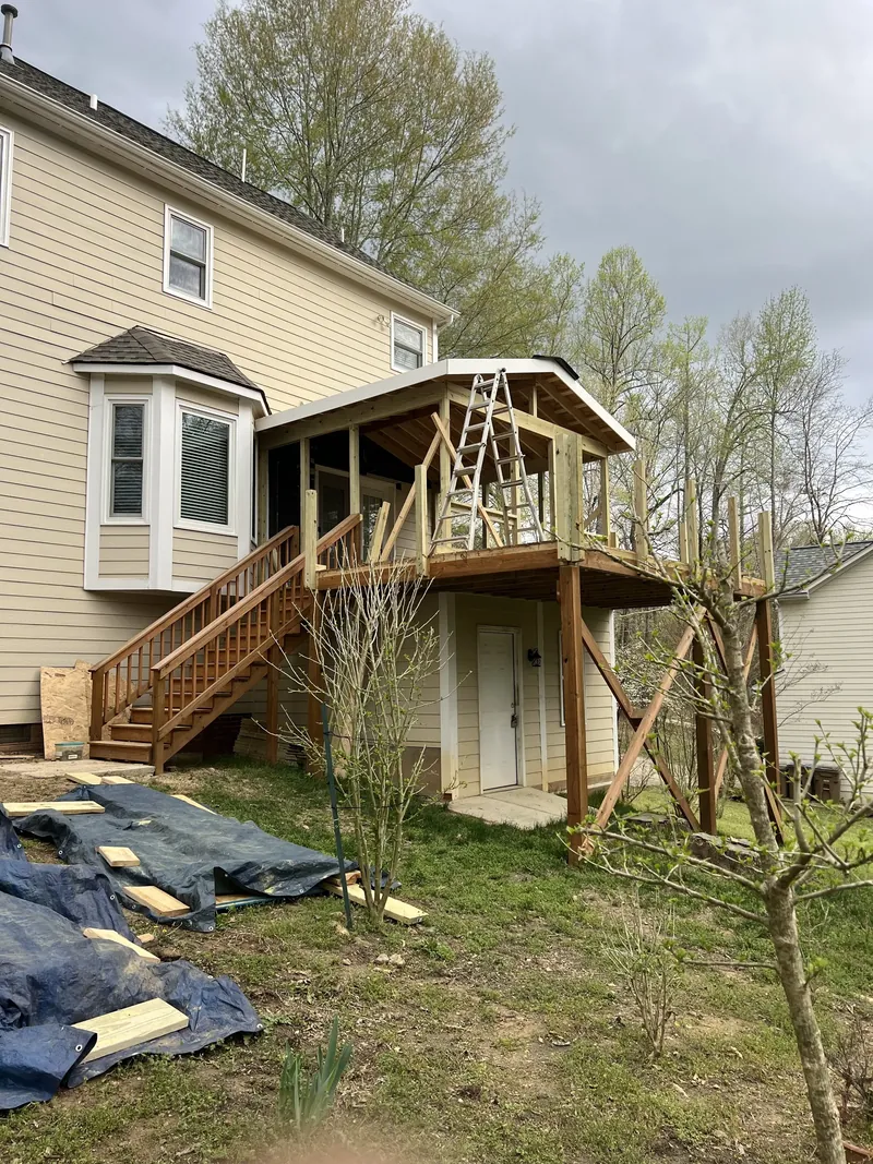 Screened porch roof and deck stairs framed in pressure treated lumber during construction